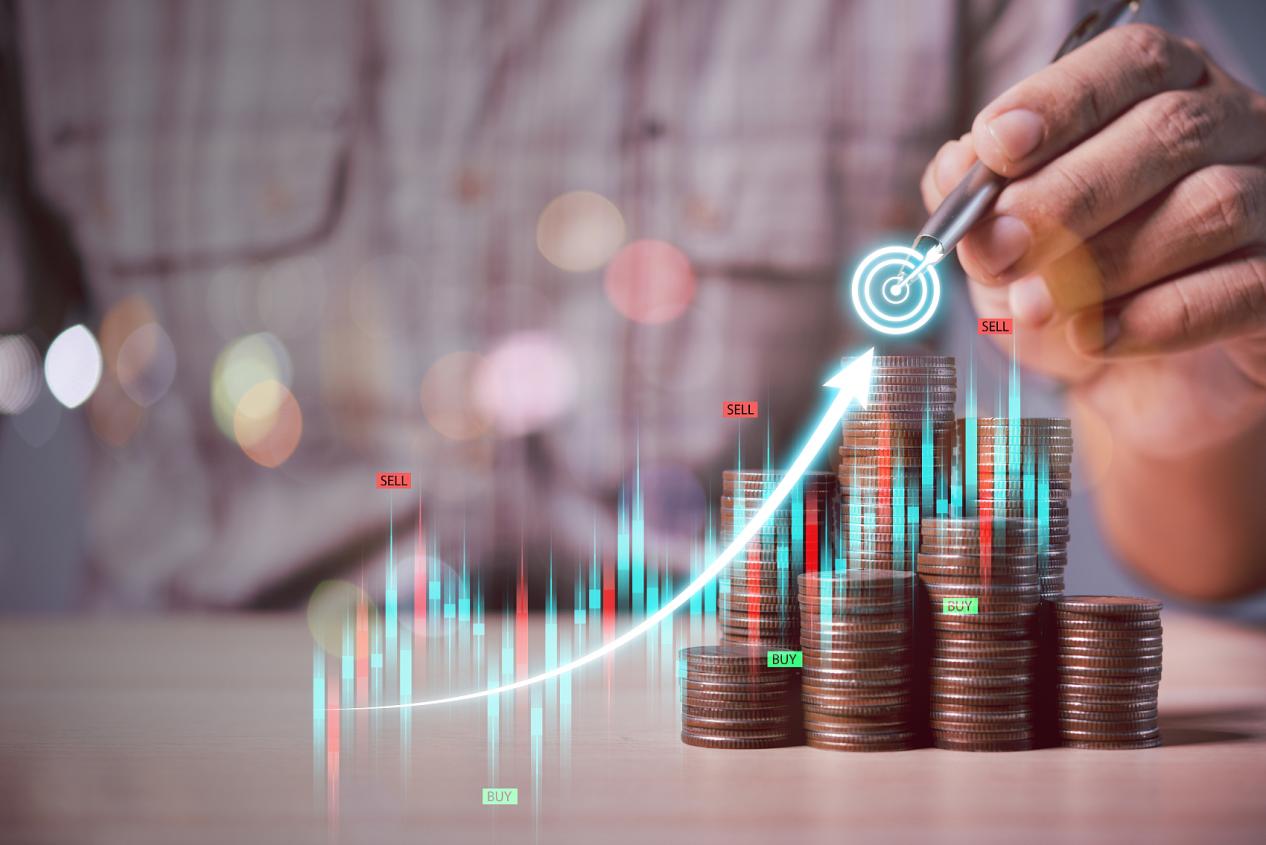 男子手握笔画商业图目标在硬币堆背景，商业和金融概念