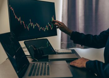 股票交易员看着屏幕上的股票市场图表，分析投资策略，金融工作与屏幕上的股票图表和指标，人们努力做出风险决策