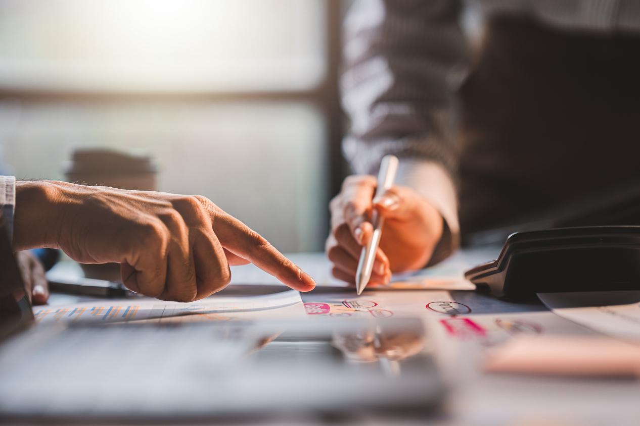 年轻同事讨论业务和价格图表分析商务人士在桌子上伟大的现代联合办公的团队合作理念。为客户计算个税