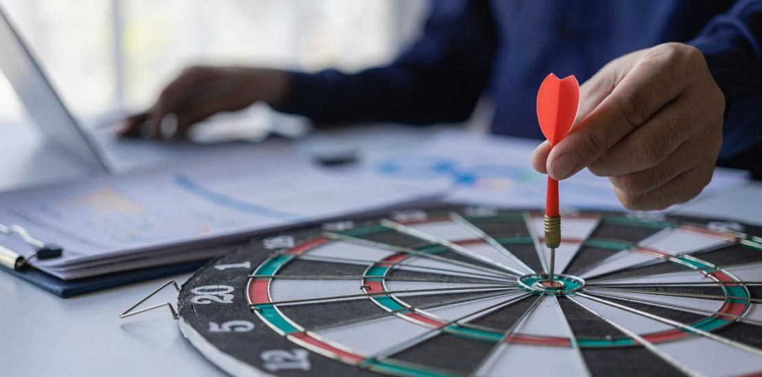 商人手持飞镖瞄准商业目标的商业目标中心，瞄准、聚焦概念，隐喻用营销或箭的概念