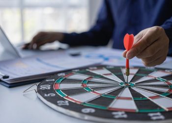 商人手持飞镖瞄准商业目标的商业目标中心，瞄准、聚焦概念，隐喻用营销或箭的概念