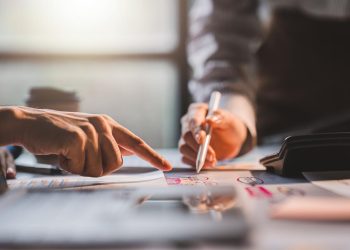 年轻同事讨论业务和价格图表分析商务人士在桌子上伟大的现代联合办公的团队合作理念。为客户计算个税