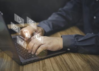 文件管理和技术概念，商人使用笔记本电脑的虚拟屏幕上的图标工作在办公室和黑暗的水泥墙背景