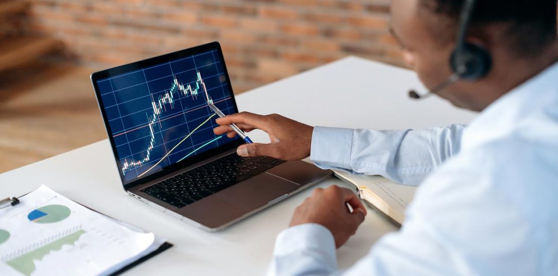 聪明专注的非洲裔美国经纪人投资者，使用笔记本电脑分析金融加密货币市场，投资电子货币，购买或出售加密货币，分析金融数据，制定策略