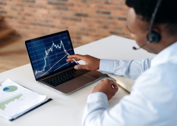 聪明专注的非洲裔美国经纪人投资者，使用笔记本电脑分析金融加密货币市场，投资电子货币，购买或出售加密货币，分析金融数据，制定策略