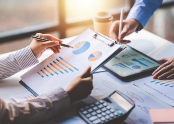 年轻同事讨论业务和价格图表分析商务人士在桌子上伟大的现代联合办公的团队合作理念。为客户计算个税