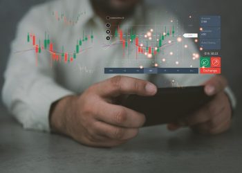 手持智能手机与股票市场图表，全息图与柱状图和不断增长的线。数字和动态变化。