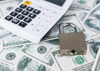 美元钞票背景上的锁和计算器